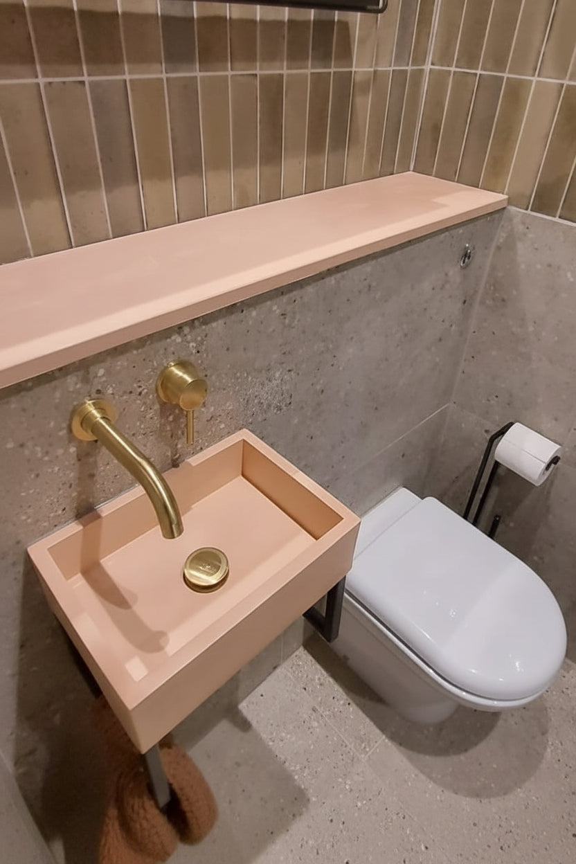 Modern bathroom featuring a concrete sink and shelf, paired with brushed bras fixtures.
