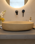 Beige concrete sink in organic pill shape in a soft tone bathroom
