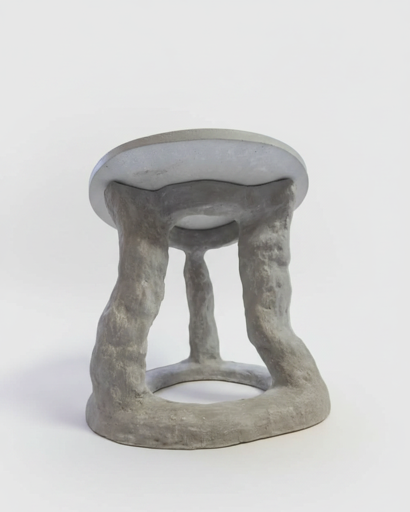 A sculptural concrete accent table with a rounded, organic base and a smooth, light gray tabletop, photographed on a seamless white studio background.
