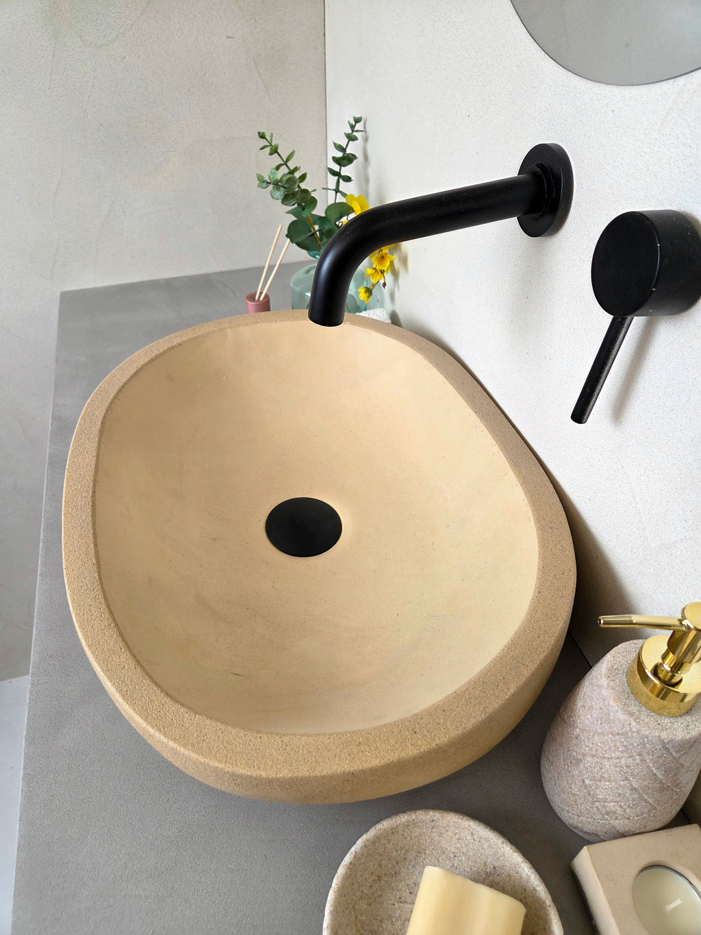 Beige concrete sink with black faucet on a bathroom counter