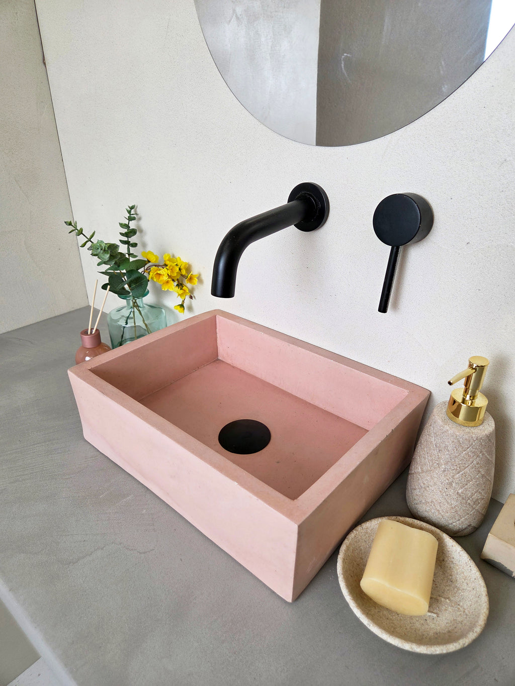 side view of pink concrete sink, countertop mounted, with bathroo maccessories