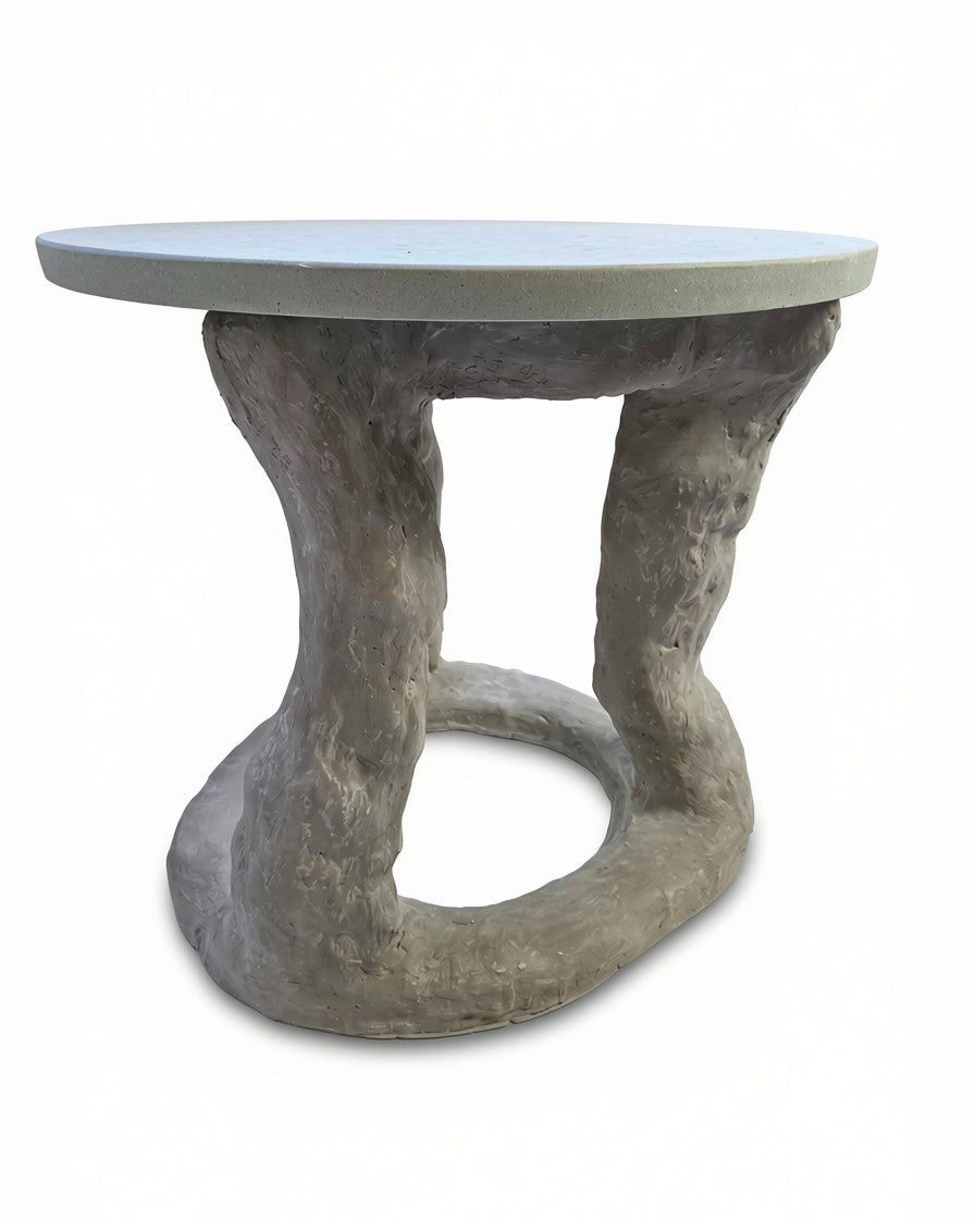 A sculptural side table featuring a smooth, light gray circular top and a textured, organic-shaped base resembling tree roots or a coiled natural form in gray and brown tones, set against a plain white background.