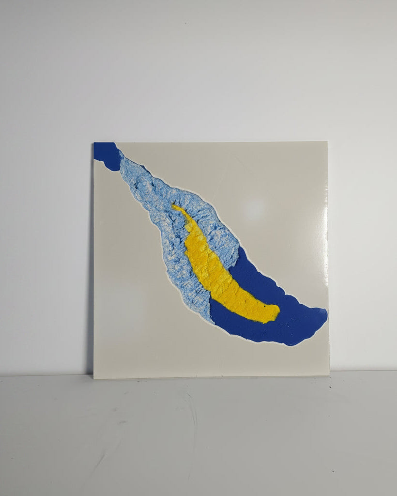 Abstract concrete art piece with blue and yellow shapes on a white background