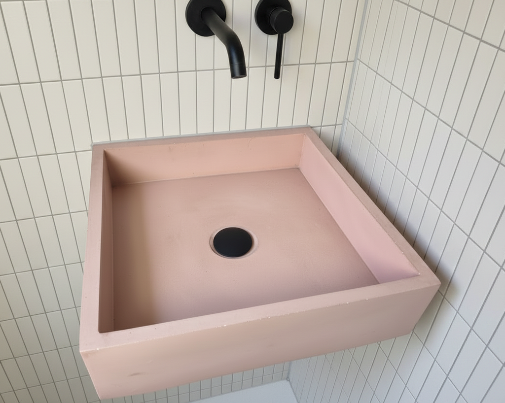 pink concrete rectangular sink wall mounted against hite tiled bathroom wall