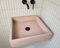 pink concrete rectangular sink wall mounted against hite tiled bathroom wall