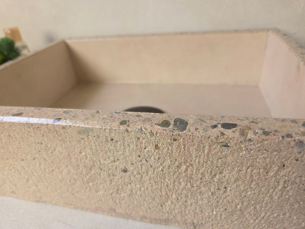 Close up of a concrete sink with polished edge and exposed aggregate and a rough finish on the exterior for added dimension texture.