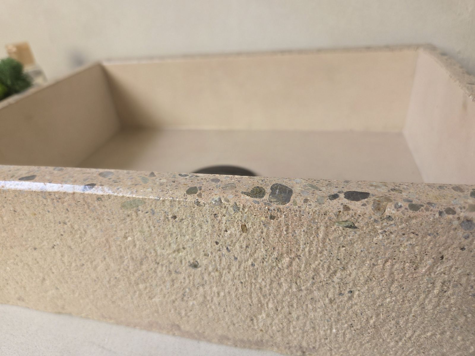 Close up of a concrete sink with polished edge and exposed aggregate and a rough finish on the exterior for added dimension texture.