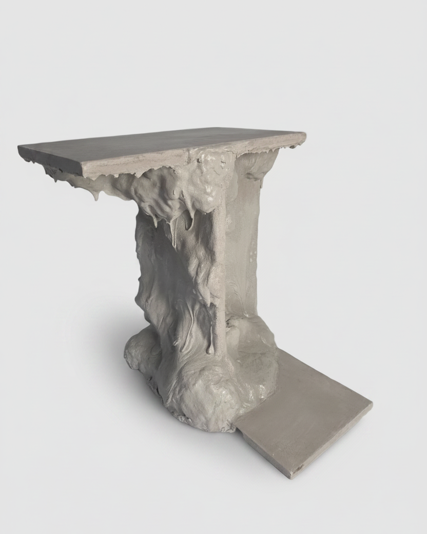 A sculptural gray side table with a flat rectangular top, a textured organic pedestal base, and a small matching side plate, shown on a light gray background.