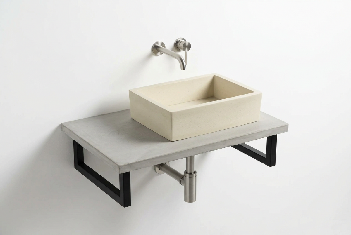 A modern wall-mounted concrete bathroom vanity with a rectangular cream basin, a light gray concrete shelf, black steel brackets, and a brushed nickel wall-mounted faucet against a white wall.