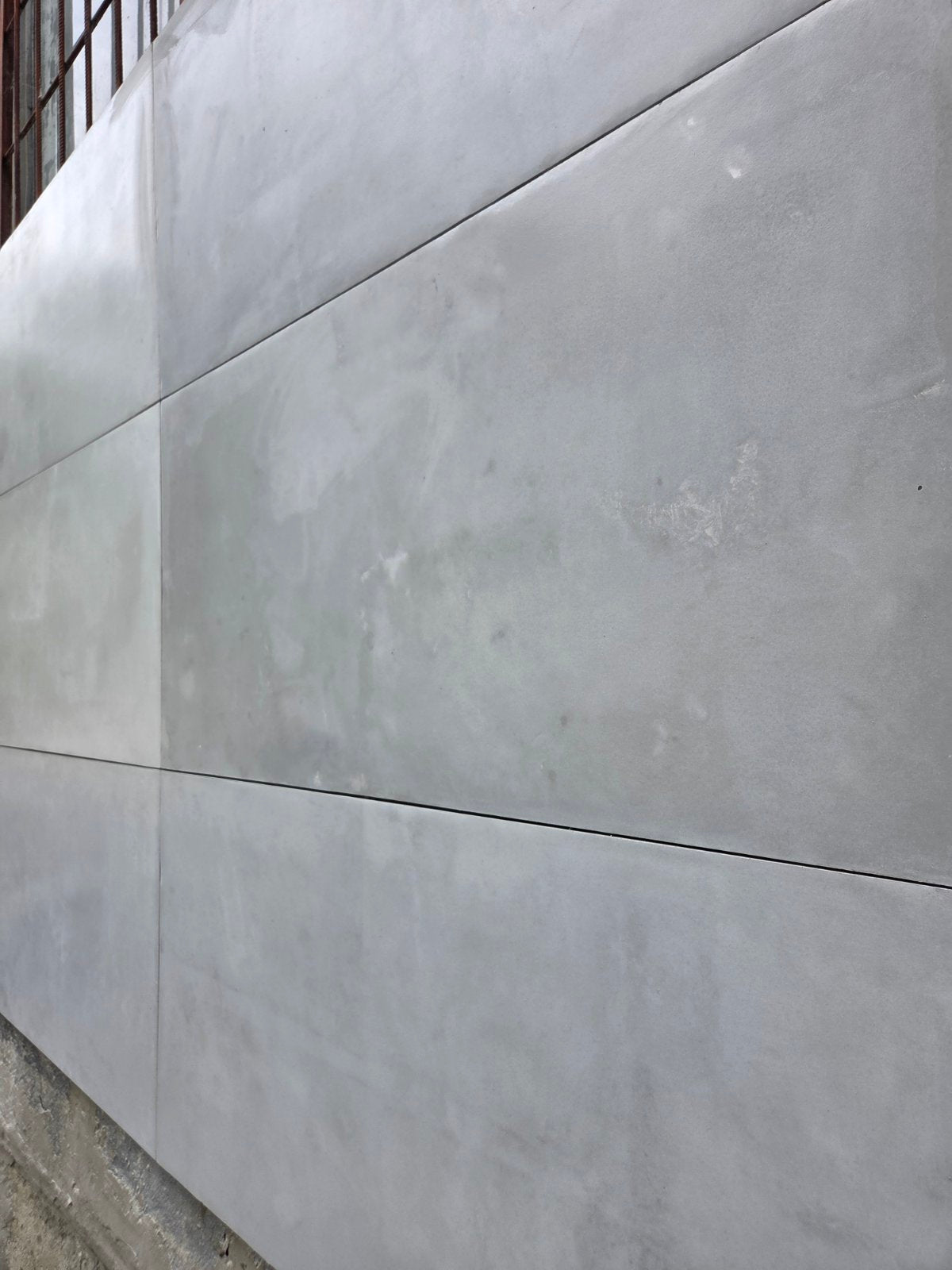 Large rectangular gray concrete panels laid out on a wall, showing a smooth matte texture with subtle natural variation.