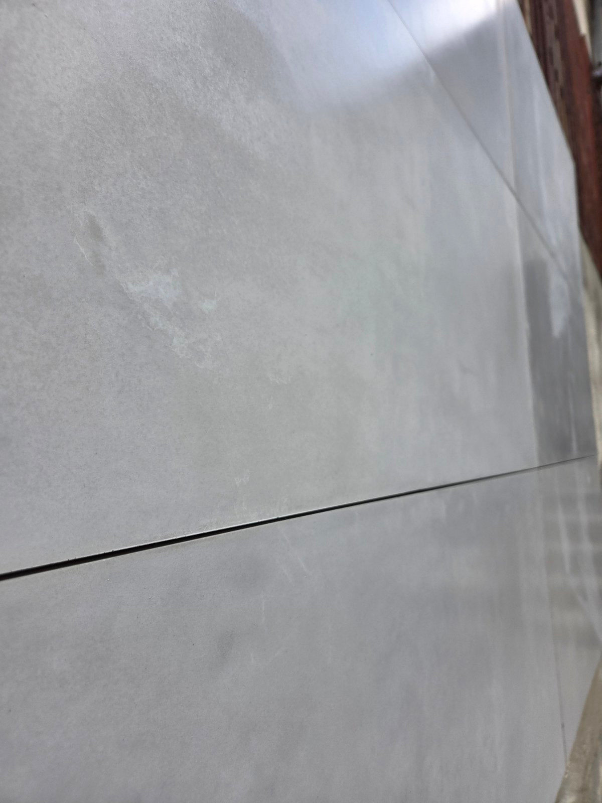 Large gray concrete tiles with a matte smooth finish, arranged side-by-side with a thin dark grout line visible.