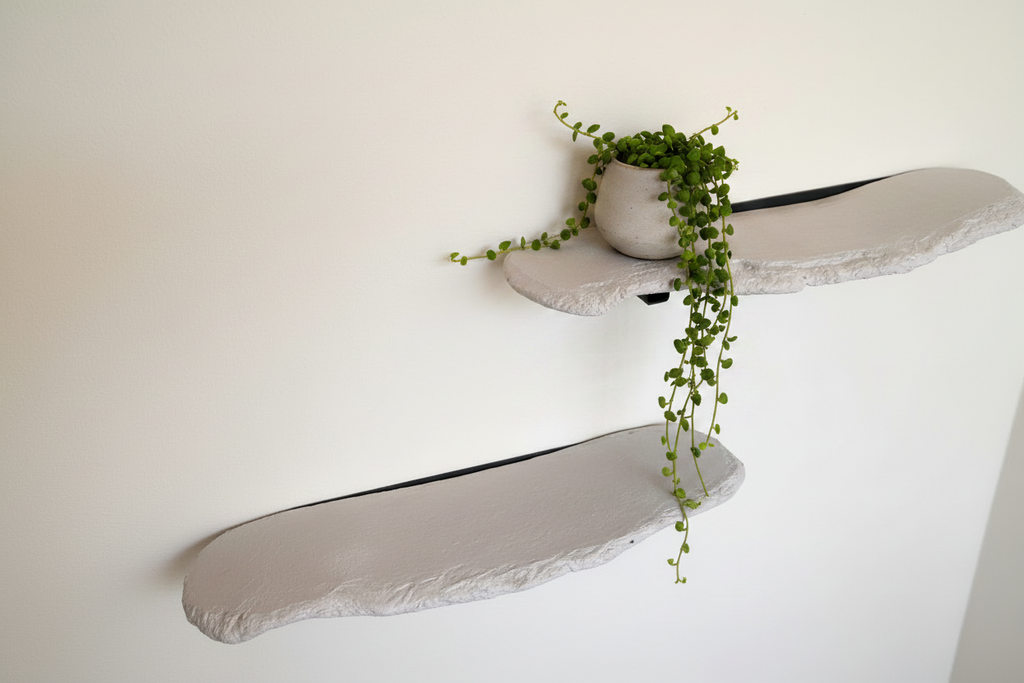Set of two organic concrete wall shelves mounted on a white wall