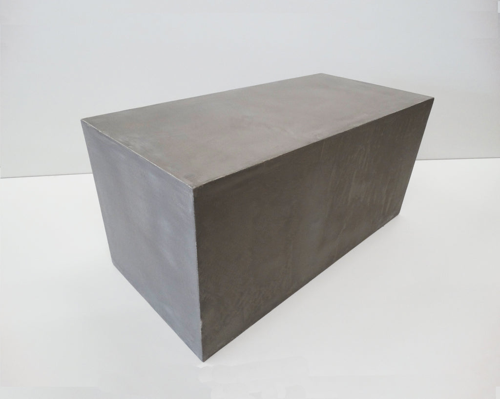 Angled side view of a grey microcement coffee table showing its rectangular block form and smooth finish.