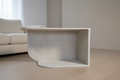 sculptural table with microcement finish and open storage on both sides in a neural living room